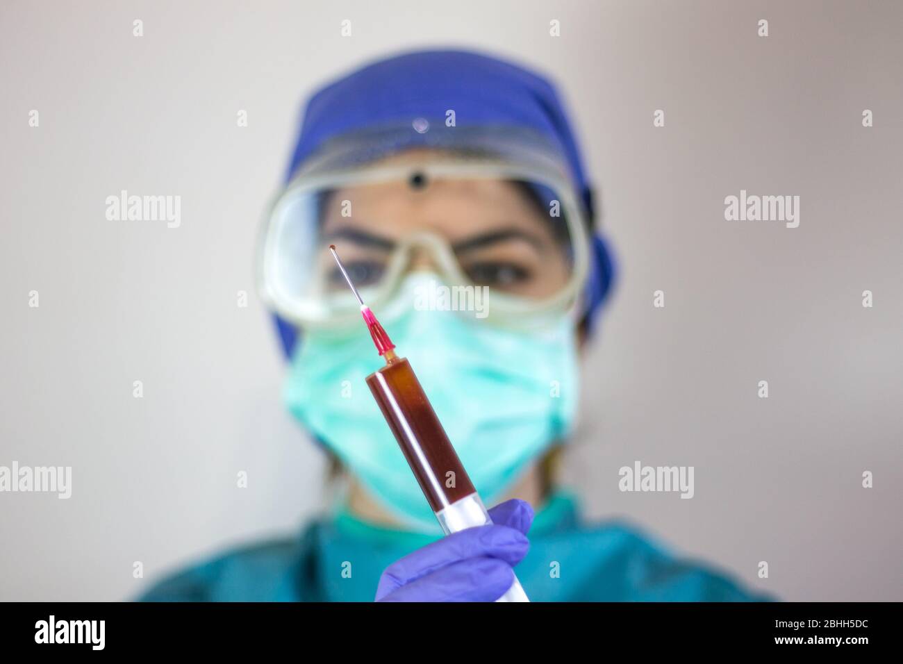 Nahaufnahme der Krankenschwester, die Blutprobe eines Patienten mit Coronavirus-positivem Patienten hält. Mit Schutzausrüstung, OP-Hut, Masken, Handschuhe, protektiv Stockfoto