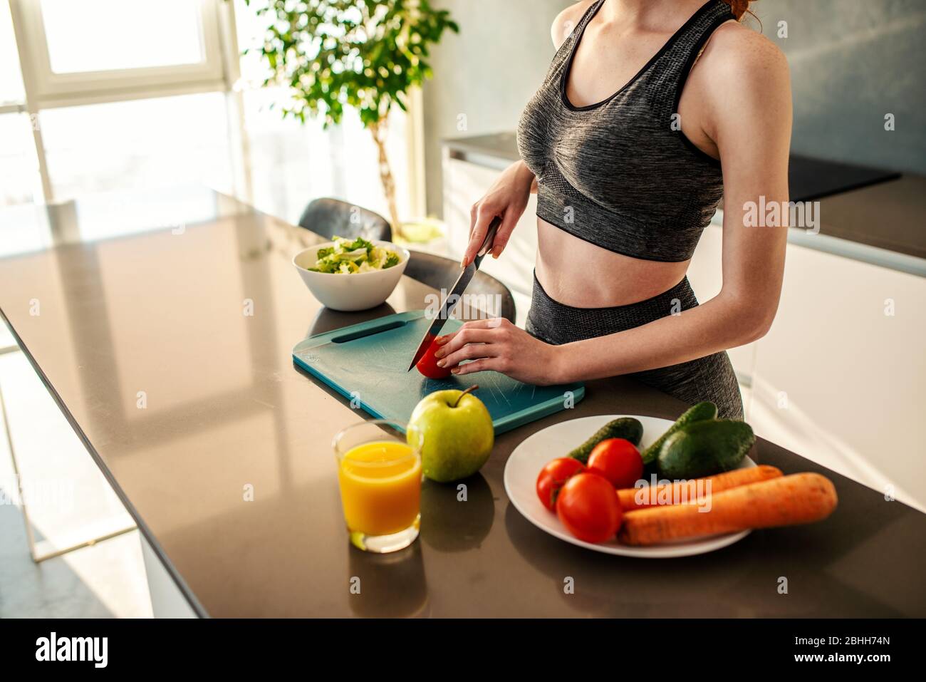 Athletisches Mädchen mit Turnkleidung isst einen Salat in der Küche Stockfoto