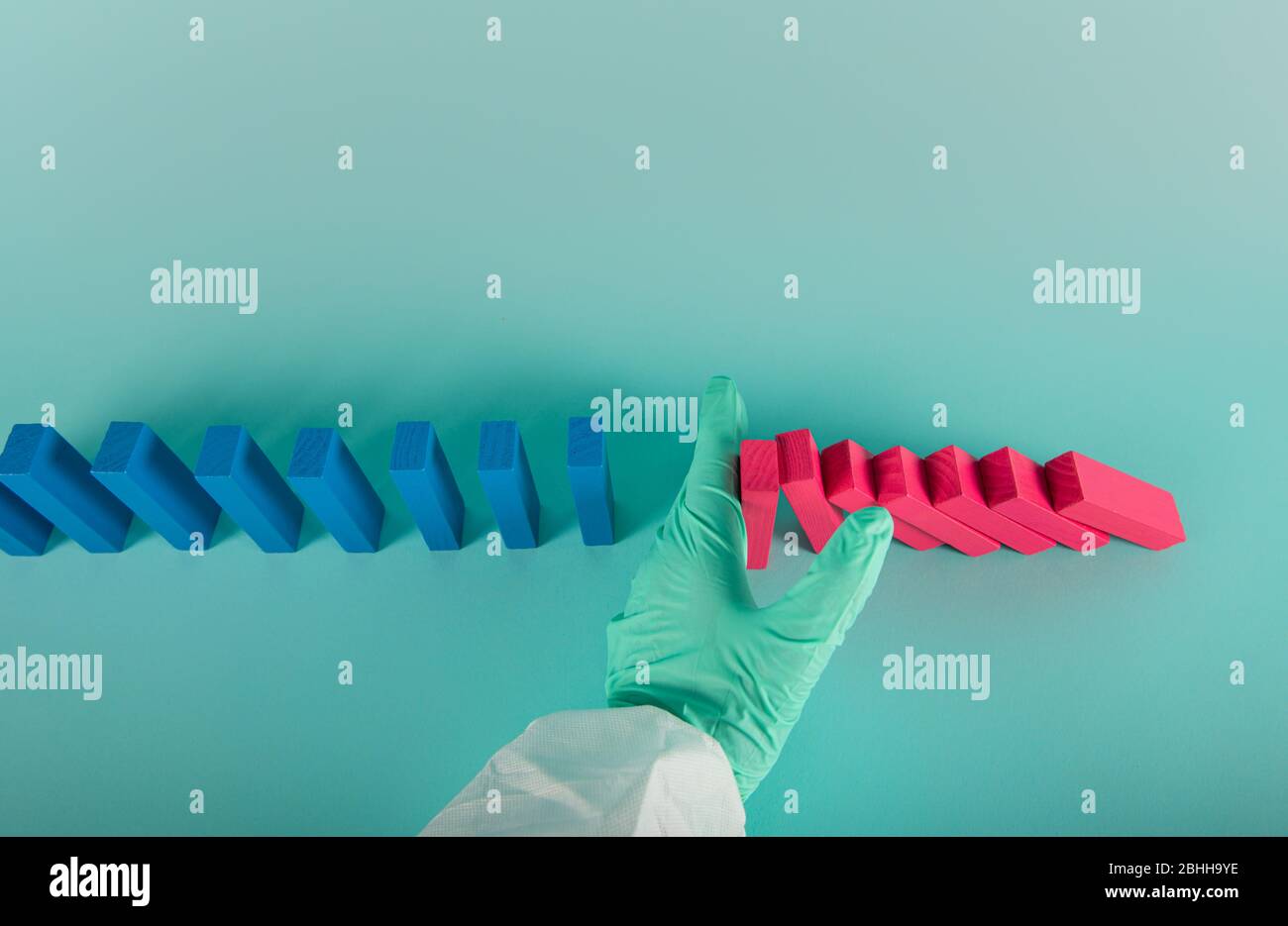 Konzept der covid19 Coronavirus Pandemie mit fallenden Kette wie ein Domino-Spiel. Ansteckung und Infektionsverlauf wurden durch eine Hand eines Arztes gestoppt. Zyan Stockfoto