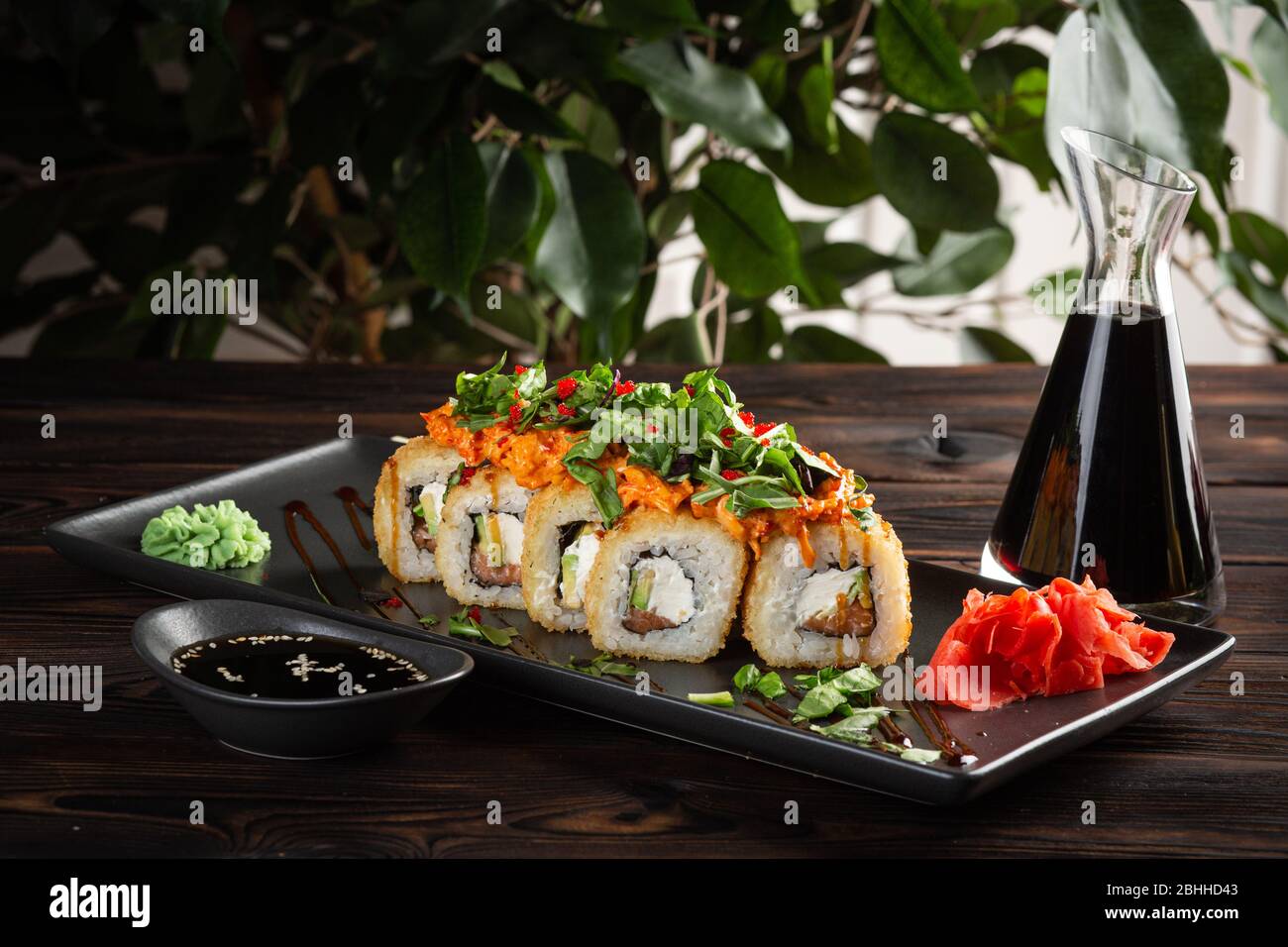 Sushi-Rolle auf einem runden Teller und Sojasoße auf dunklem Holzhintergrund Stockfoto