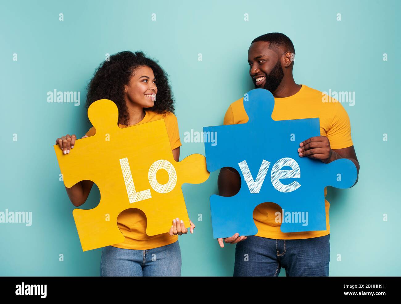 Paar mit Puzzles in Hand über hellblauen Hintergrund. Integrationskonzept, union, Beziehung und Partnerschaft Stockfoto