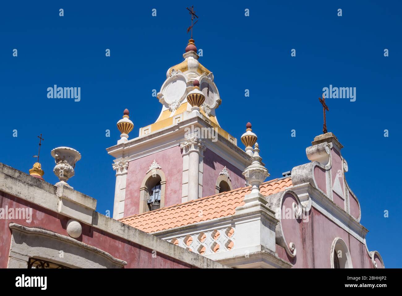 Helle farbe der Wände in bordeaux, weiße Details. Palast Estoi im Stil des Neo-Rokoko erbaut. Blick auf den Turm. Strahlend blauer Himmel. Estoi, Portugal. Stockfoto