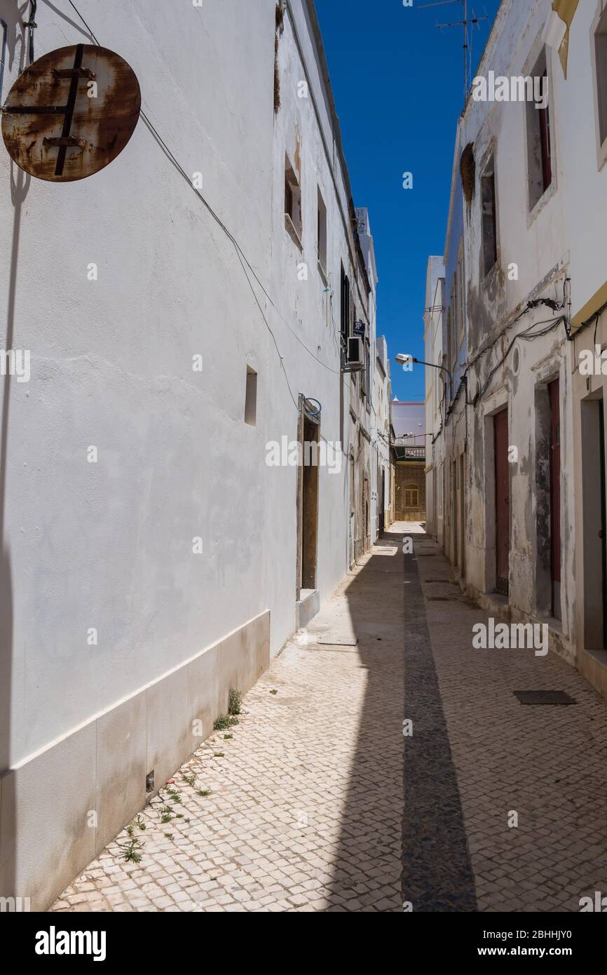 Enge Straße einer Altstadt an einem sonnigen Tag mit blauem Himmel. Häuser mit meist weißer Fassade. Estoi, Portugal. Stockfoto