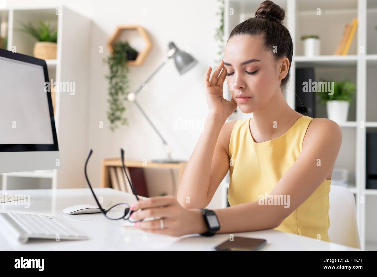 Verwirrt junge Brünette Geschäftsfrau berühren Tempel während der Migräne in modernen Büro leiden Stockfoto
