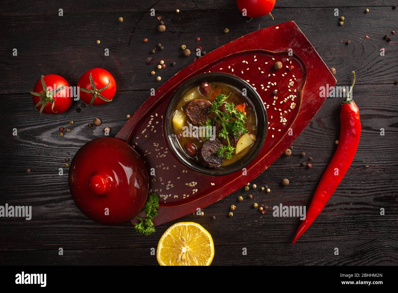 Gemüseeintopf mit Kartoffeln und Fleisch in einem Topf mit Petersilie auf dunklem Holzhintergrund dekoriert Stockfoto