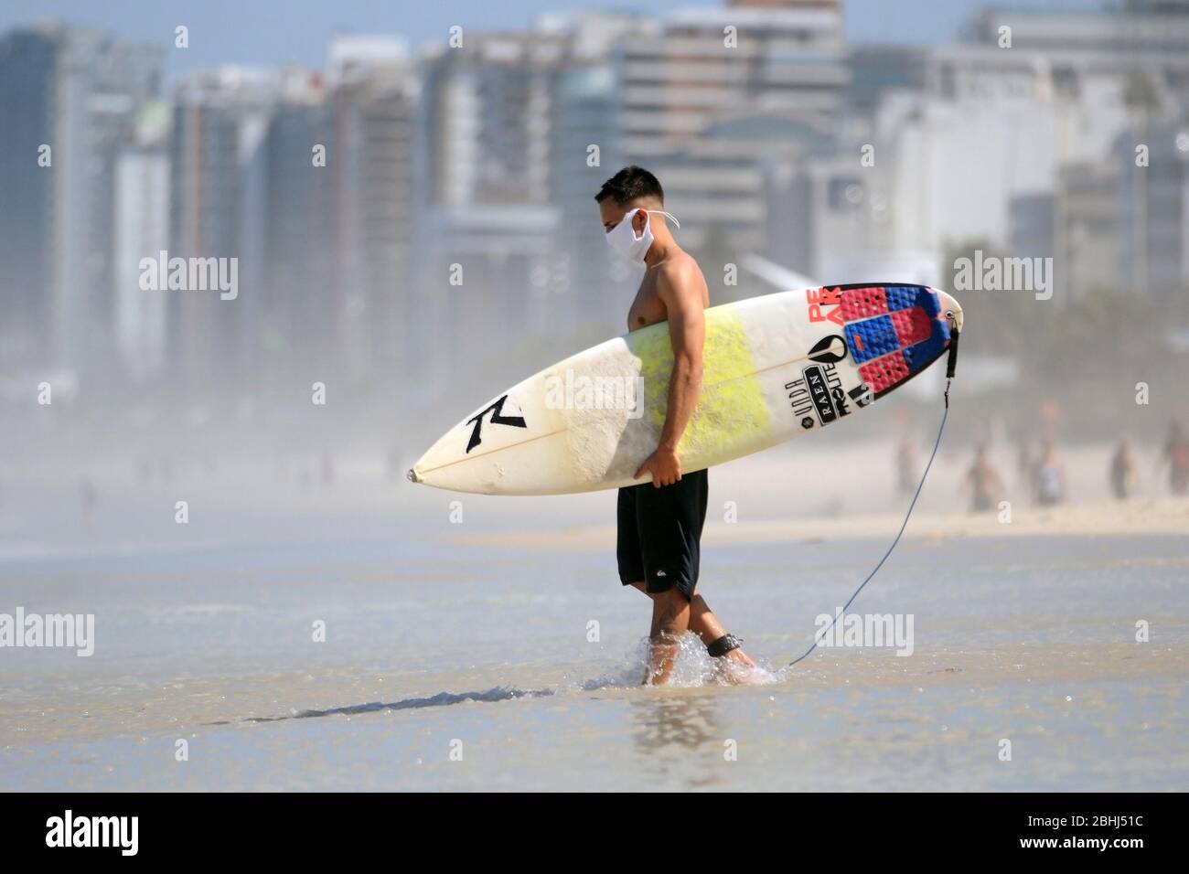 Rio de Janeiro, Brasilien, 25. April 2020. Surfer reiten Welle mit Coronavirus-Schutzmaske, am Strand Barra da Tijuca, im Westen der Stadt ​​the Stockfoto