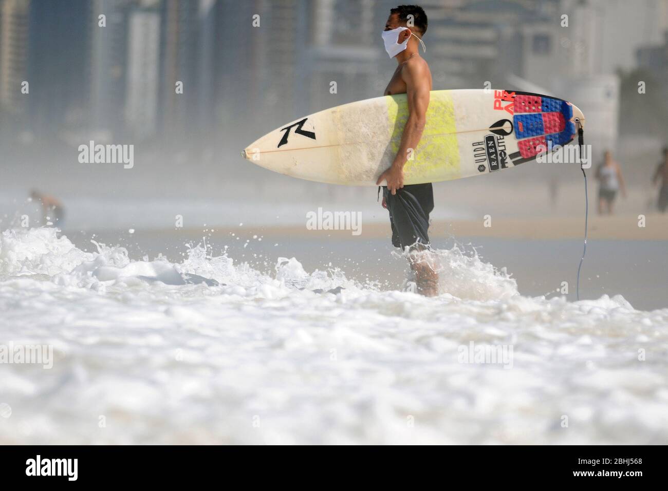 Rio de Janeiro, Brasilien, 25. April 2020. Surfer reiten Welle mit Coronavirus-Schutzmaske, am Strand Barra da Tijuca, im Westen der Stadt ​​the Stockfoto