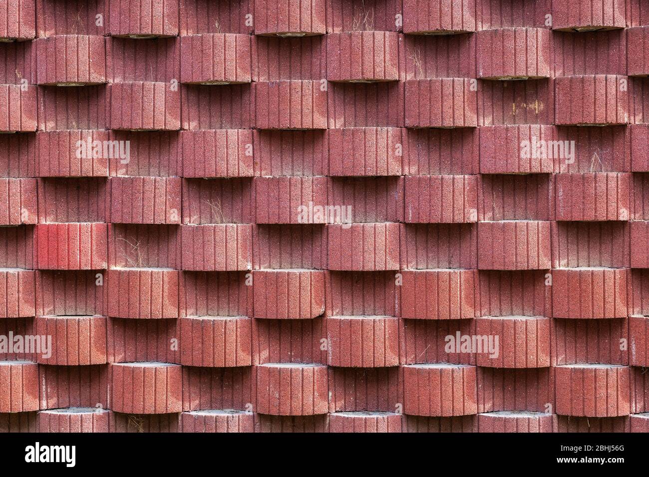 Abstrakt rötlichen Wand Hintergrund mit Muster von hervorstehenden und konkaven abwechselnden ovalen Formen und gerillten vertikalen Linien Stockfoto