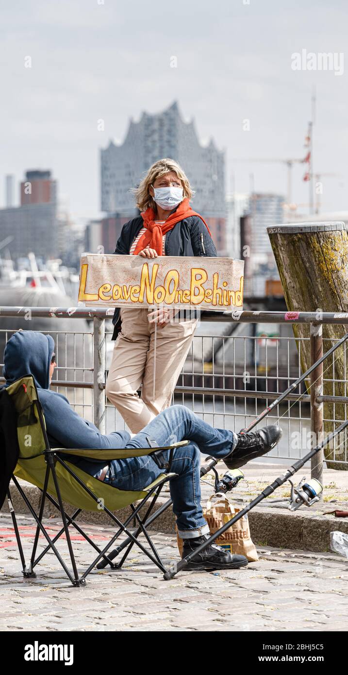 Hamburg, Deutschland. April 2020. Ein Demonstrator hält ein Schild mit der Aufschrift "Leave no one behind". Aktivisten der Hilfsorganisation Seebrücke demonstrieren in einer Kette von 20 Standorten von der Fischauktionsallee bis zu den Deichtorhallen mit Schildern und Transparenten für eine Auflösung der Flüchtlingslager in Griechenland. Quelle: Markus Scholz/dpa/Alamy Live News Stockfoto