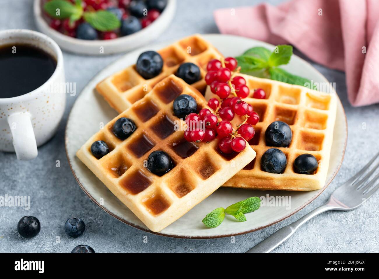 Viereckige belgische Waffeln mit Beeren und Ahornsirup. Süßes Frühstück Stockfoto