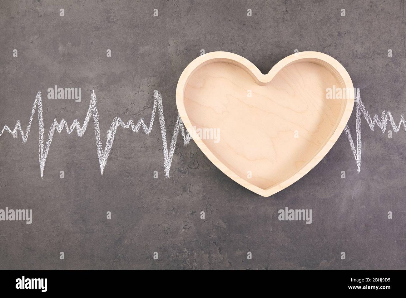 Herz in Holzform mit Kardiogramm über Tisch. Gesundheitskonzept Stockfoto