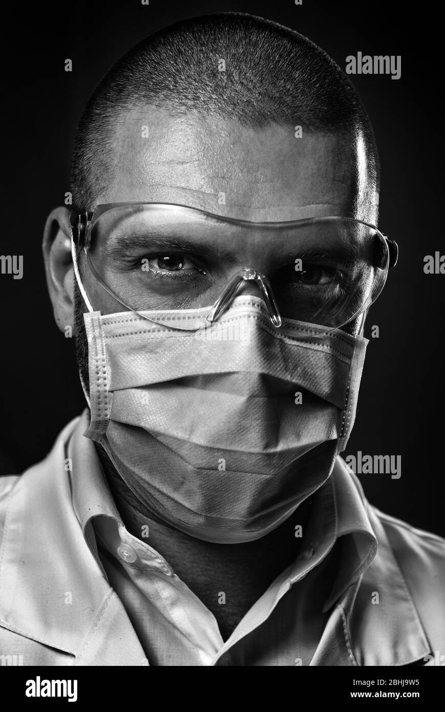 Nahaufnahme Porträt kaukasischen zuversichtlich männlichen Arzt Gesicht in blauen Maske Schutzbrille Blick auf Kamera. Medizinische Fachkraft, Therapeut Chirurg Stockfoto