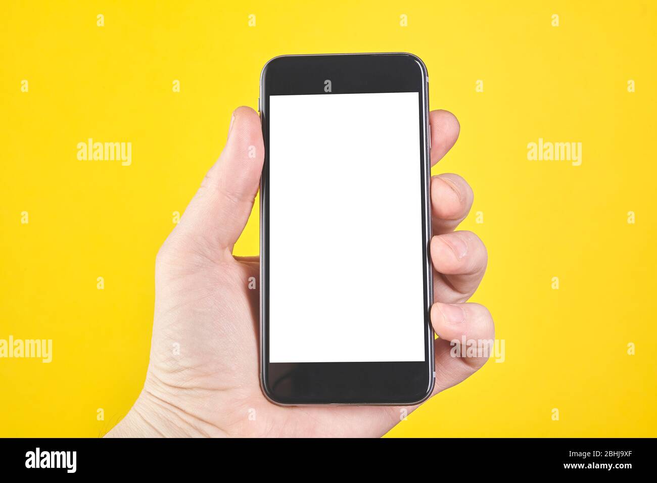 Halten Sie das Smartphone auf gelbem Hintergrund. Nahaufnahme Stockfoto