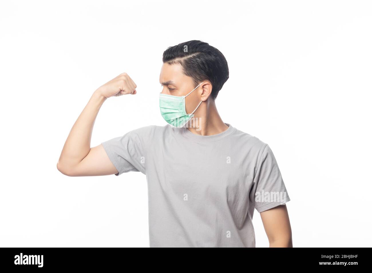 Junger Asian Mann in hygienischer Maske zeigt Stärke, um Infektionen zu verhindern, 2019-nCoV oder Coronavirus. Atemwegserkrankungen in der Luft, wie z. B. PM 2.5-Kämpfe Stockfoto