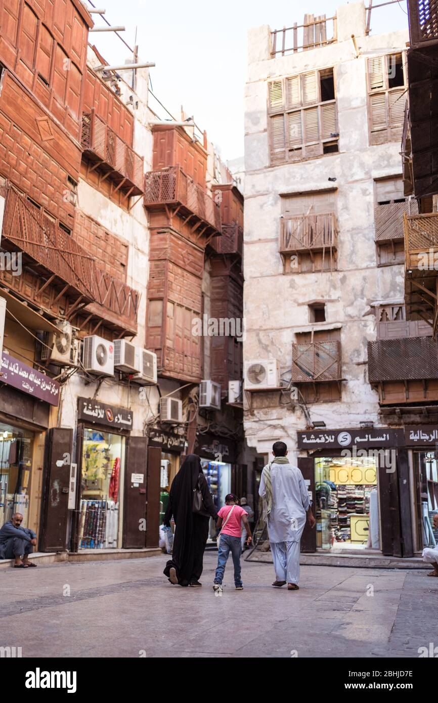 Jeddah / Saudi Arabien - 16. Januar 2020: Muslimische Familie, die vor einem Holzgebäude in der historischen Altstadt von Al-Balad läuft Stockfoto