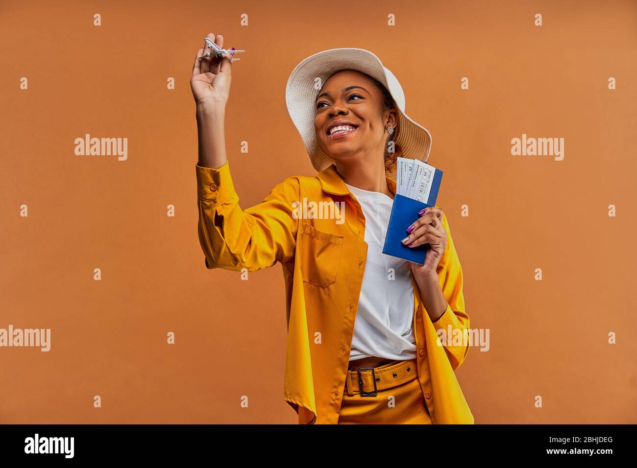 Glückliche Dame im Hut mit einem Flugzeug mit einem Pass mit Tickets. Stockfoto
