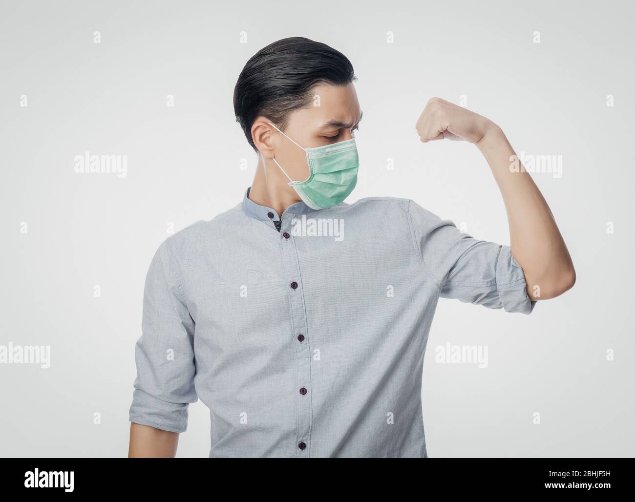 Junge asiatische Geschäftsmann in hygienischen Maske zeigt Stärke, um Infektionen zu verhindern, 2019-nCoV oder Coronavirus. Atemwegserkrankungen in der Luft, wie z. B. PM 2.5 Stockfoto