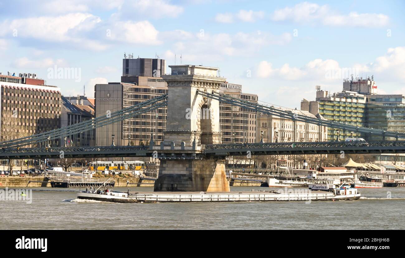 BUDAPEST, UNGARN - MÄRZ 2018: Ein langer Industriekahn, der unter der Kettenbrücke durch die Donau im Stadtzentrum von Budapest fährt Stockfoto