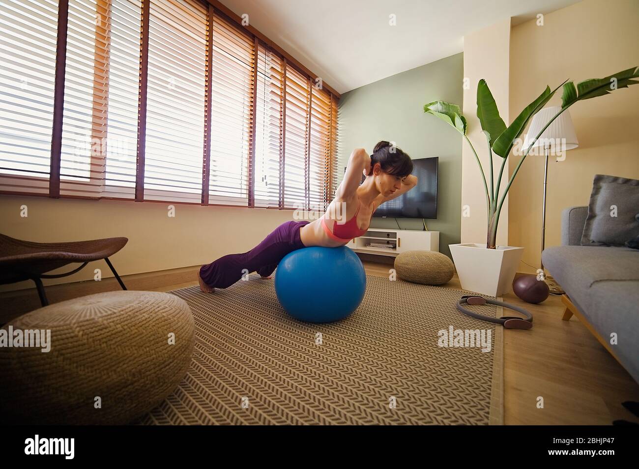 Frau, die Yoga in ihrer Wohnung vor dem Fenster praktiziert Stockfoto