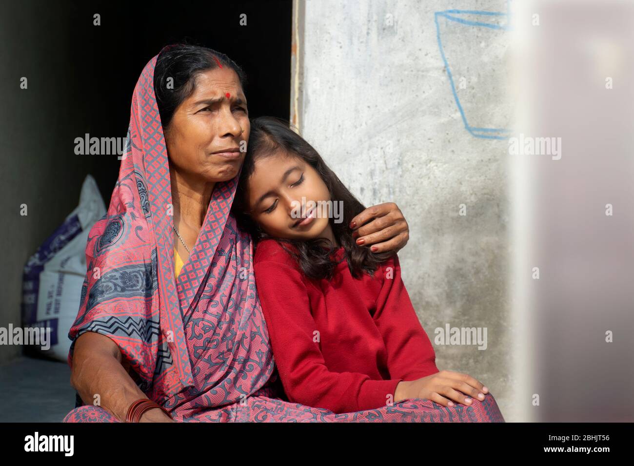 Großmutter umarmt Enkelin, nachdem sie ihre Haare kämmt Stockfoto