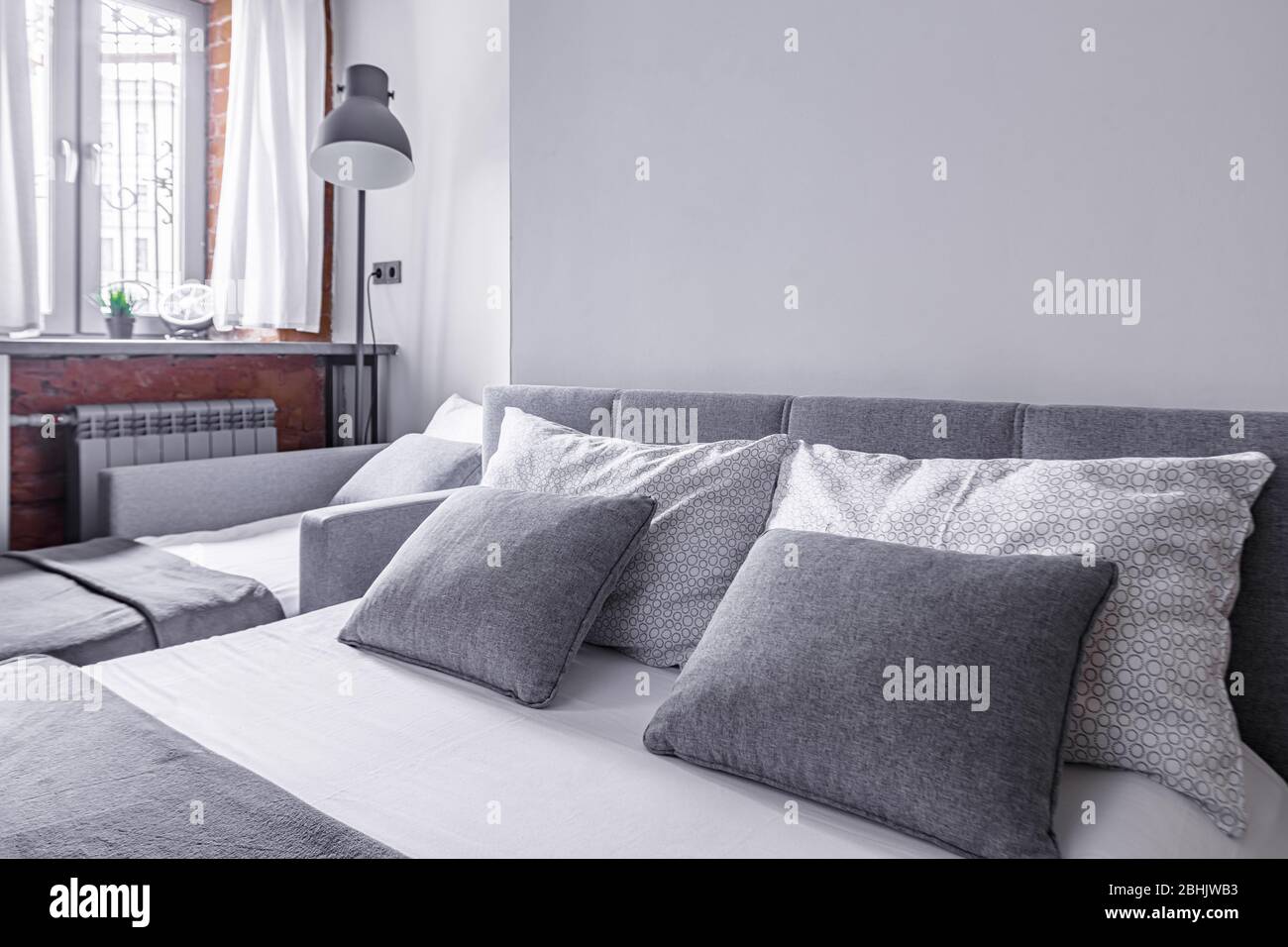 Kissen auf dem Bett und Nachttisch in gemütlichen, komfortablen Schlafzimmer in grauer Farbe Stockfoto