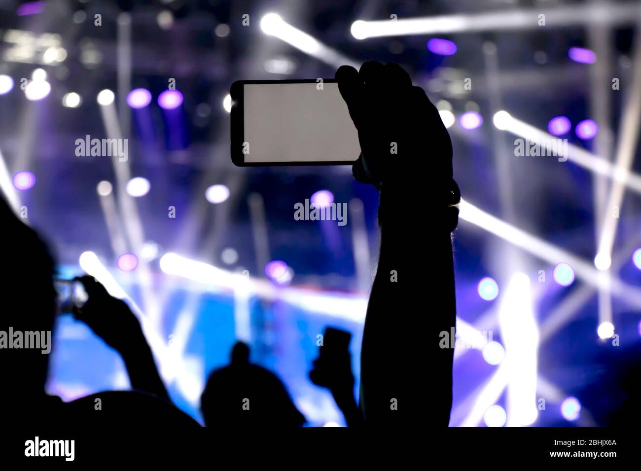 Das Sammeln digitaler Speicher verliert Fähigkeit, Gegenwart, Silhouette eines Mannes Hand schießen das Konzert mit seiner smart phone Stockfoto