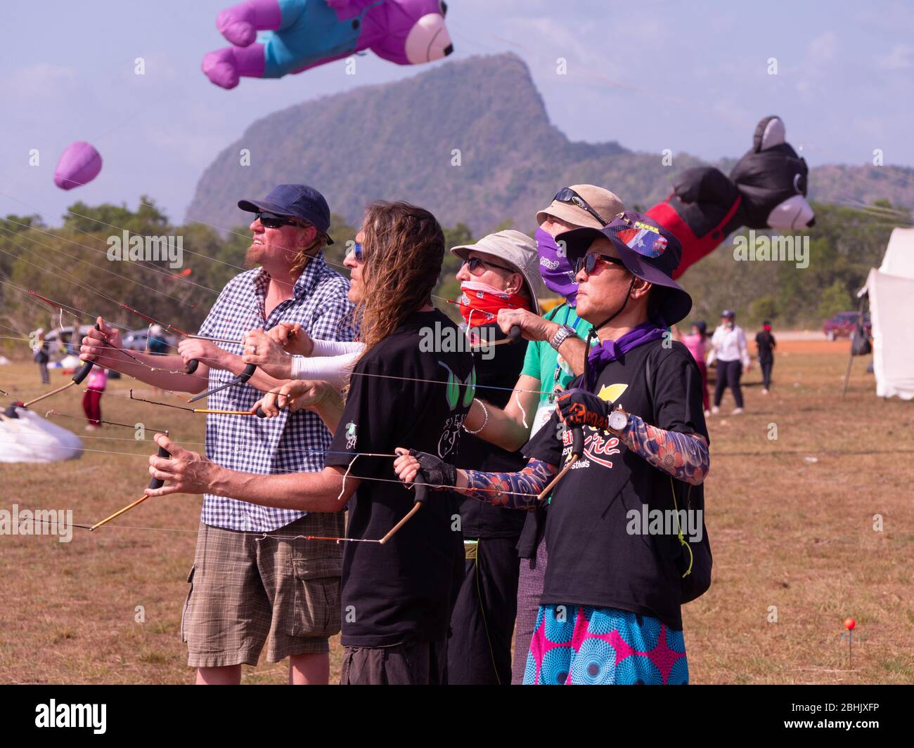 Fünf Drachen-Flyer fliegen Quad-Line-Sport-Drachen auf Satun International Kite Festival in Satun, Thailand. Stockfoto