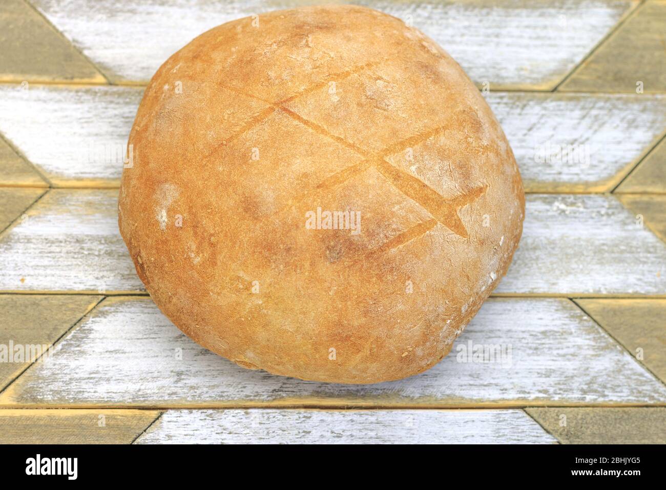 Gerade gebacken ein rundes Brot mit Weizenmehl und Sauerteig auf einer Holzfläche mit weißen Mustern gemacht Stockfoto