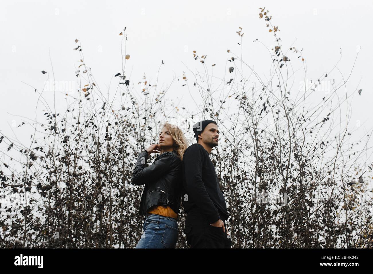 Mann und Frau stehen mit dem Rücken zueinander auf dem Hintergrund von Büschen Stockfoto