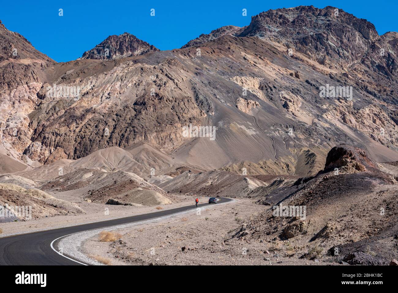 Ein einsam älterer Radfahrer hält sich auf dem Aufstieg entlang des Artist's Palette Drive im Death Valley National Park durch Stockfoto