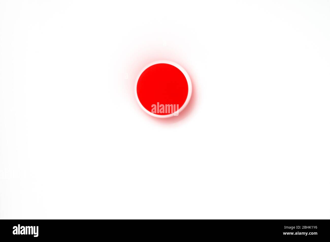 Roter Punkt auf weißem Hintergrund sieht es aus wie Japan Flagge. Seine Farbe Tropfen auf die Milchoberfläche. Stockfoto