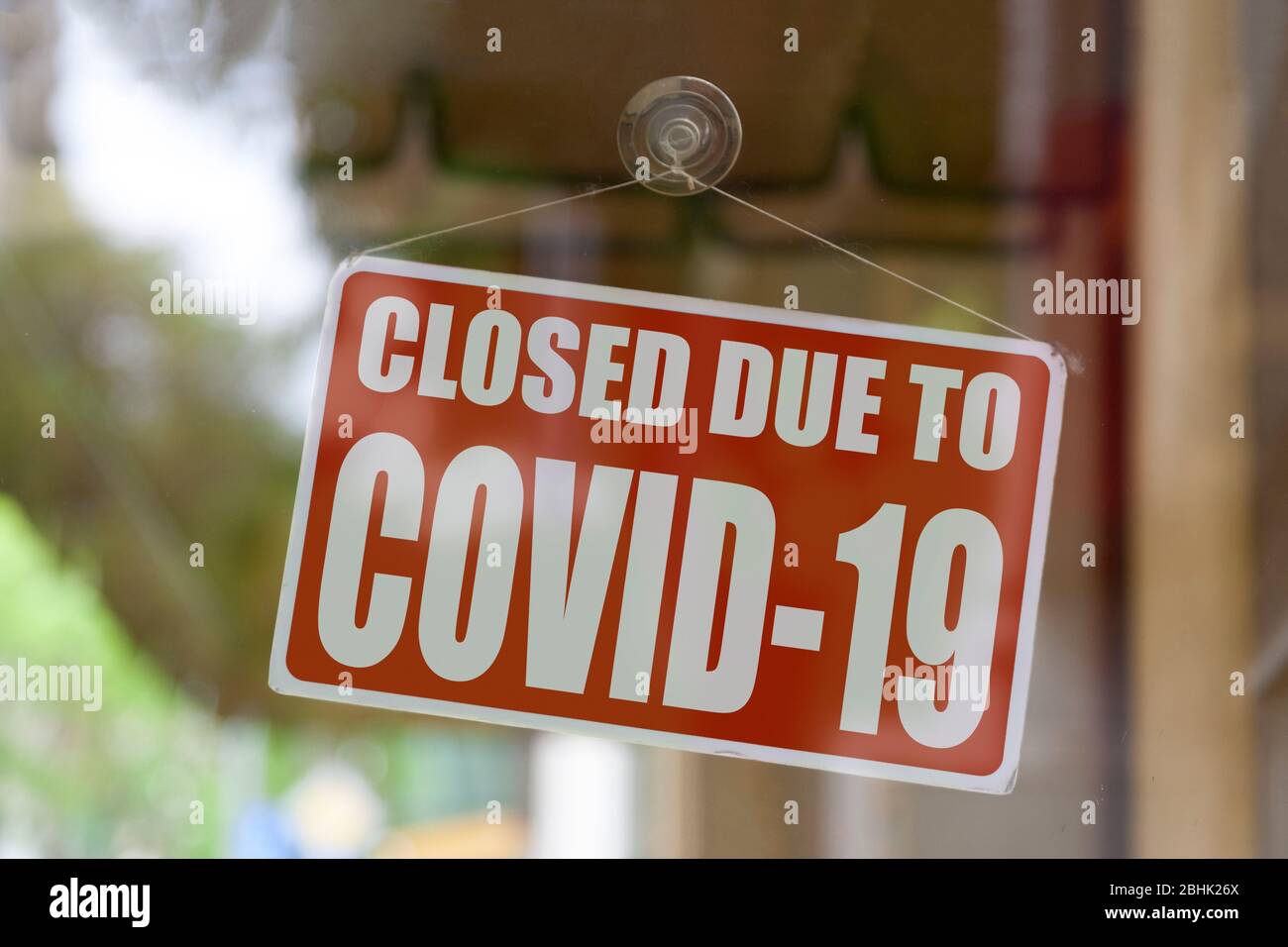 Nahaufnahme auf einem roten, geschlossenen Schild im Fenster eines Shops, das die Meldung "geschlossen aufgrund von Covid-19" anzeigt. Stockfoto