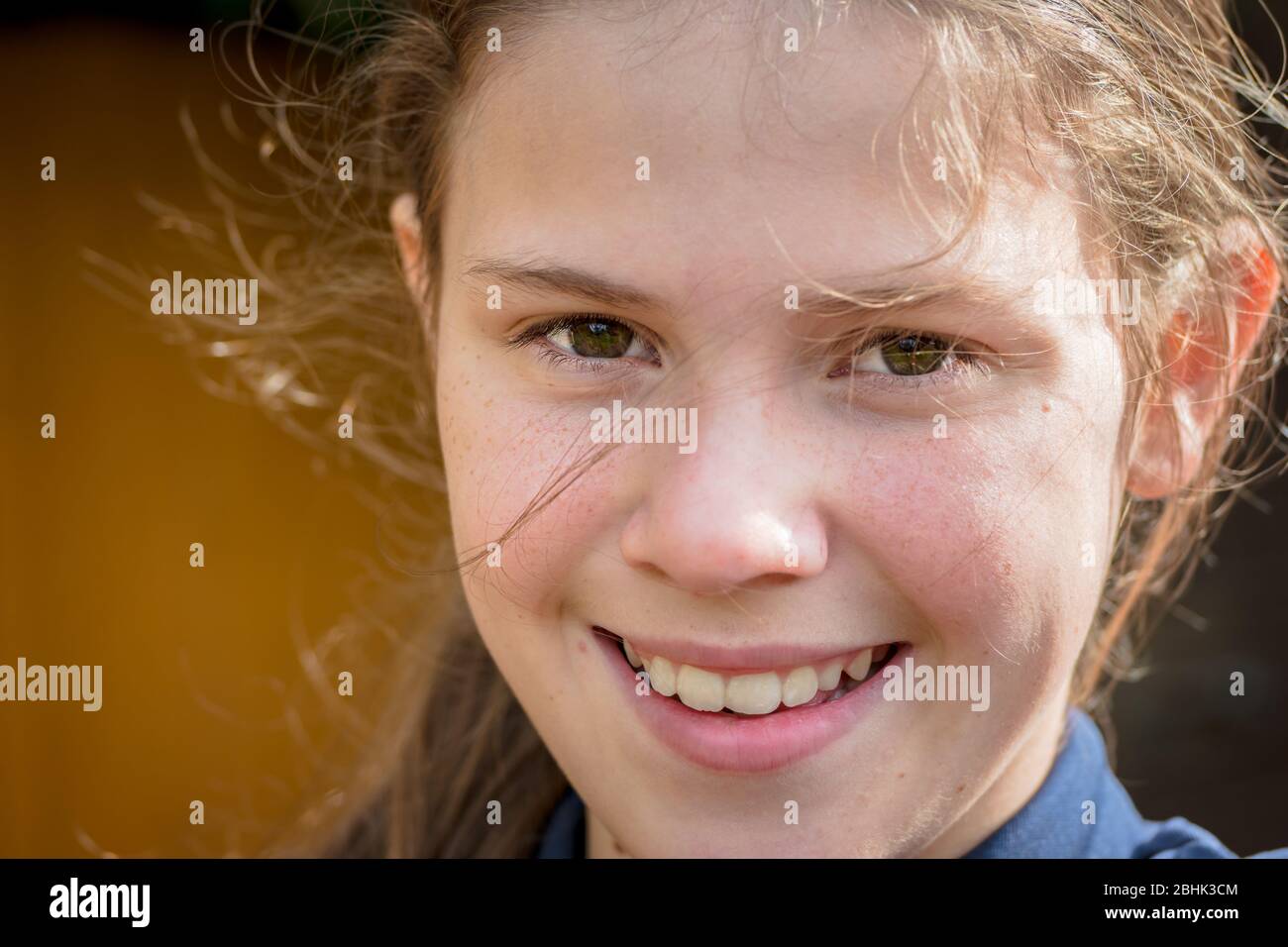 Ein Porträt eines frisch-Gesicht Teenager-Mädchen, lächelnd in einer natürlichen windgepeitschten sonnigen Umgebung Stockfoto