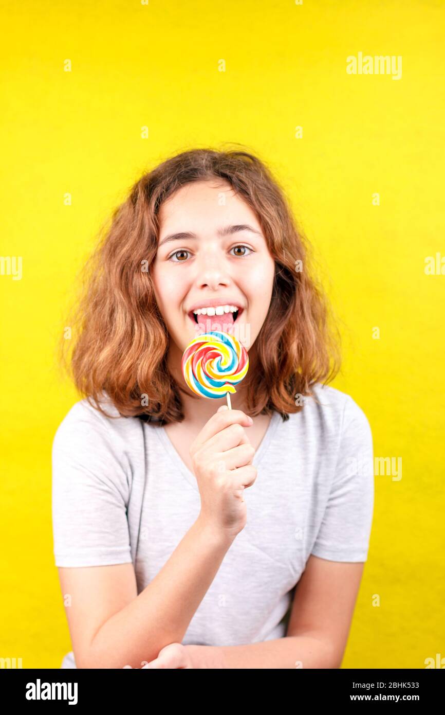 Teenager-Mädchen leckt mehrfarbigen runden Lollipop Stockfoto