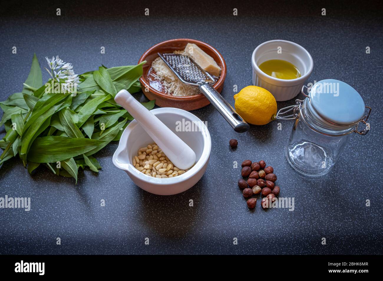 Zutaten für die Herstellung von hausgemachtem Bärlauch-Pesto durch Mahlen von gezüftetes Laub mit Olivenöl, Zitronensaft, Pinienkernen, Haselnüssen und Parmesan Stockfoto