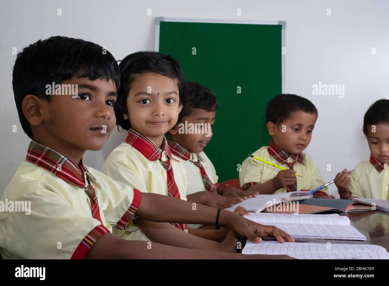 Junge Grund- oder Grundschulkinder sitzen an ihren Schreibtischen in einem Klassenzimmer Stockfoto
