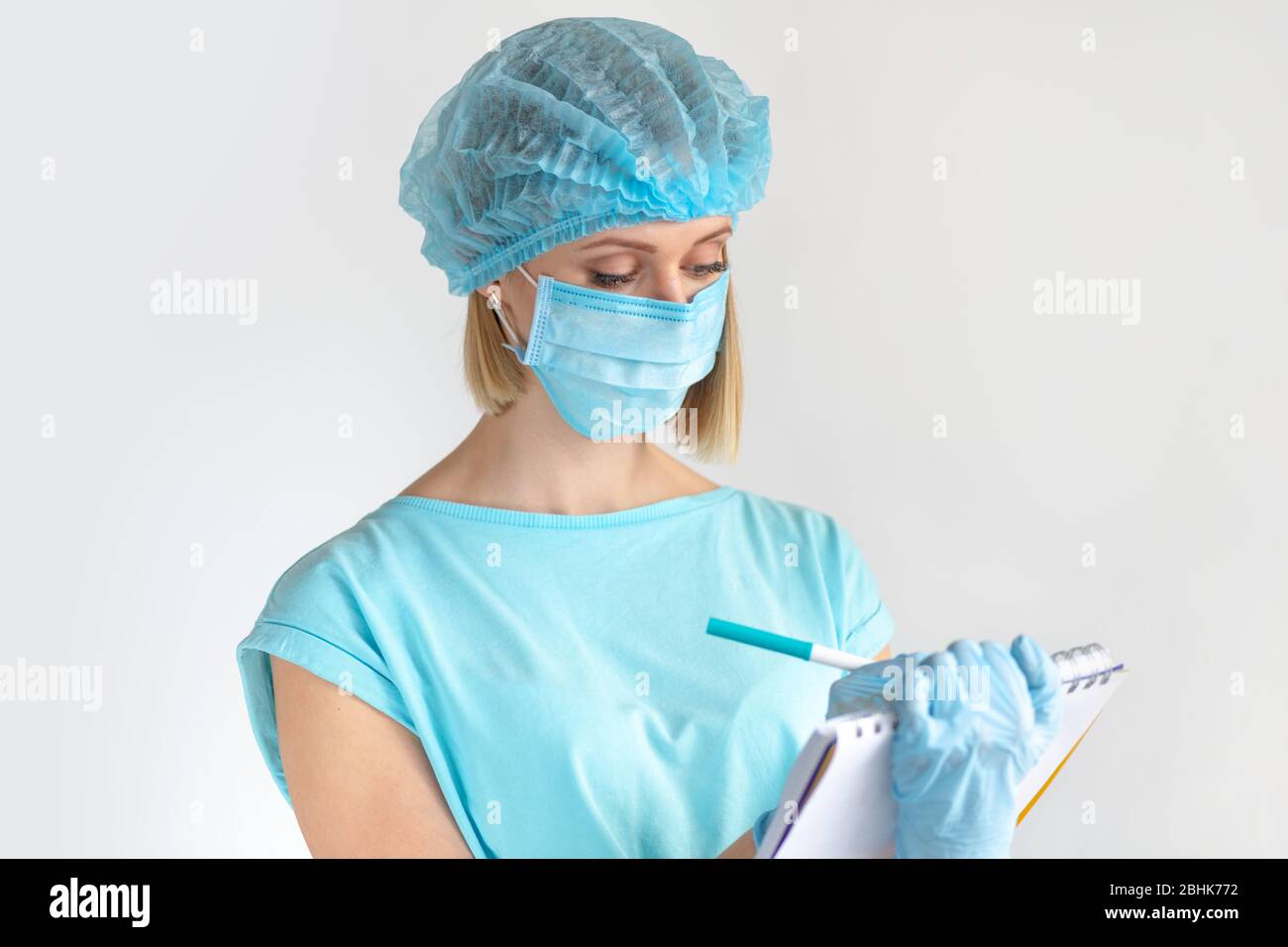 Junge Ärztin, die einen medizinischen Bericht auf einem Clipboard schreibt, medizinische Fachkräfte auf weißem Hintergrund. Gesundheitskonzept Stockfoto