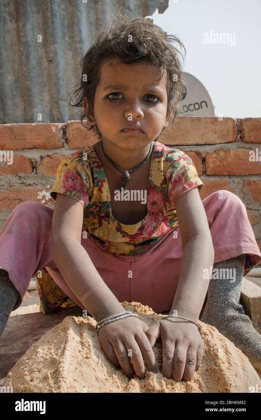 Armes Mädchen auf dem Land spielt mit Sand in indien Stockfoto