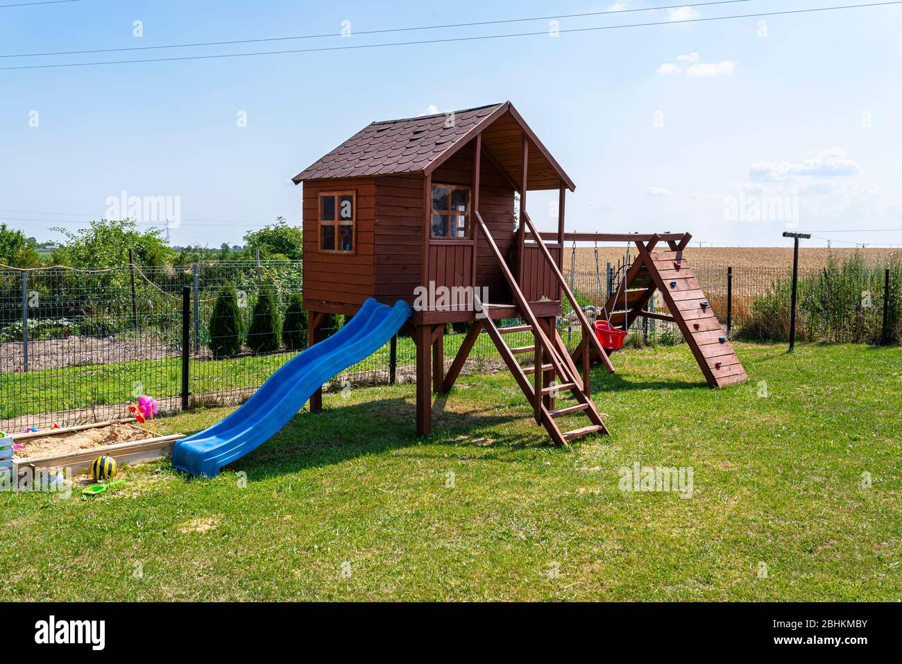 Kinderspielplatz am Hausgarten, sichtbares Holzhaus, schöner Frühlingstag. Stockfoto