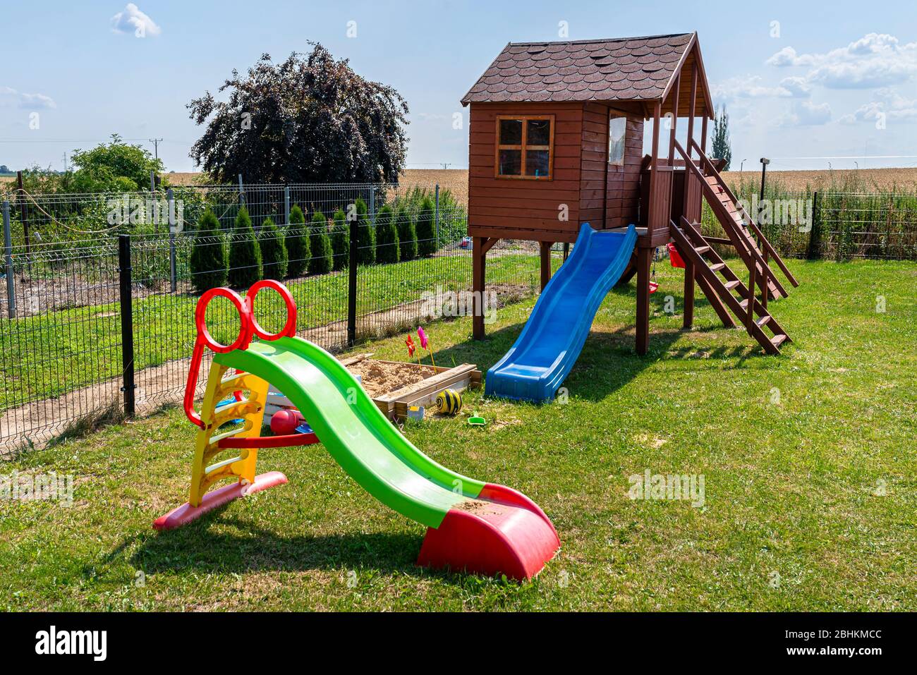 Kinderspielplatz am Hausgarten, sichtbares Holzhaus, schöner Frühlingstag. Stockfoto