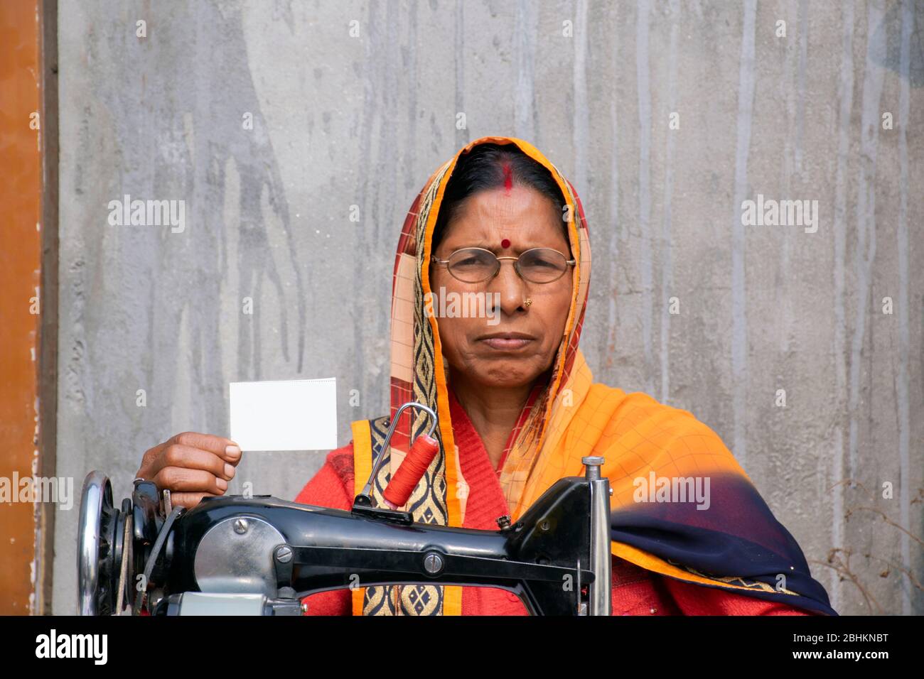 Frau auf einer Nähmaschine, die Kleidung in einem ländlichen indischen Dorf macht Stockfoto