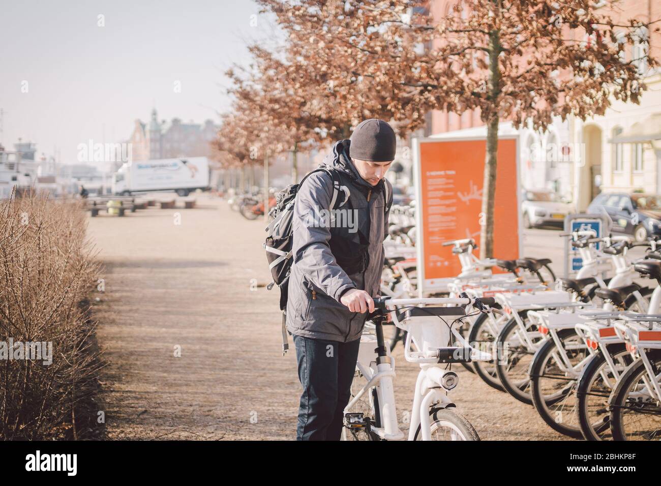 Man mietet in Kopenhagen elektrisches weißes Fahrrad. E-Fahrrad-Verleih Station. Männer geparkte City-Fahrräder zu mieten, sagen, sparen CO2 und grüne Energie. Junger Mann Stockfoto