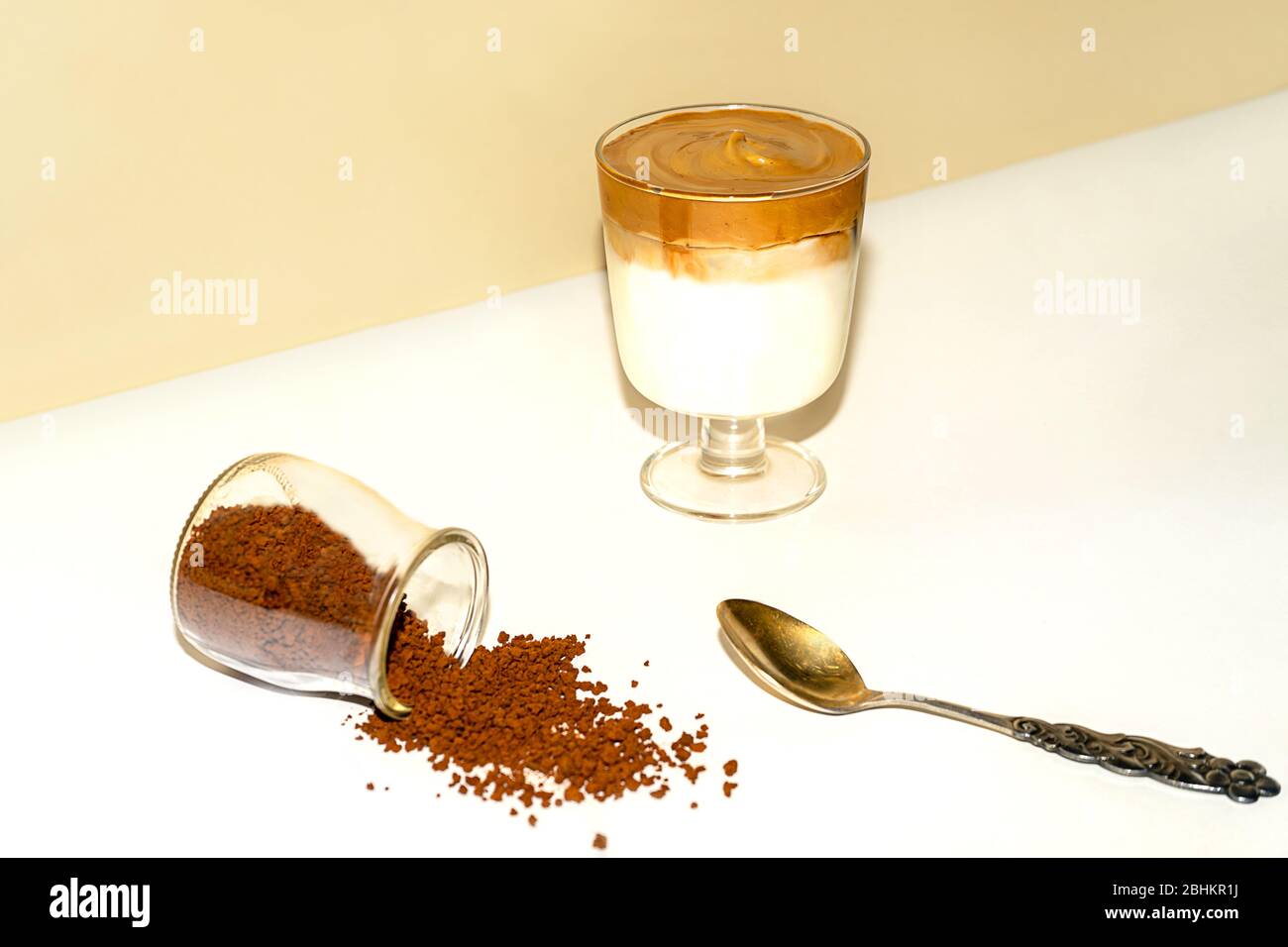 Tasse eisgekühlter Dalgona Kaffee, modischer flauschiger cremiger Schlagkaffee auf einem trendigen farbigen Hintergrund. Stockfoto