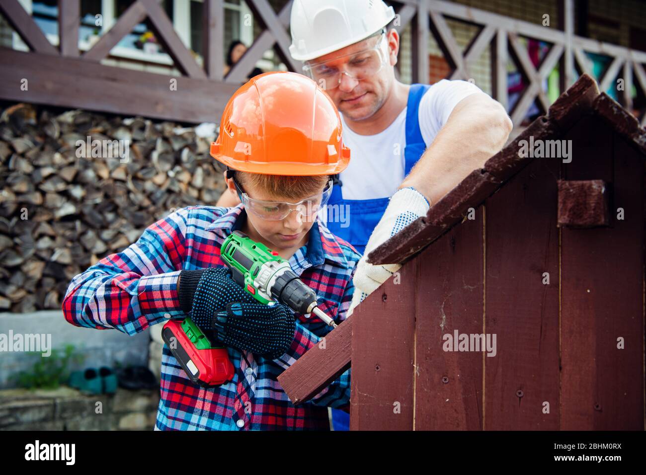 Vater und Sohn bauen gemeinsam ein hundehütte. Vater lehrt seinen Sohn, den elektrischen Schraubendreher zu benutzen. Stockfoto