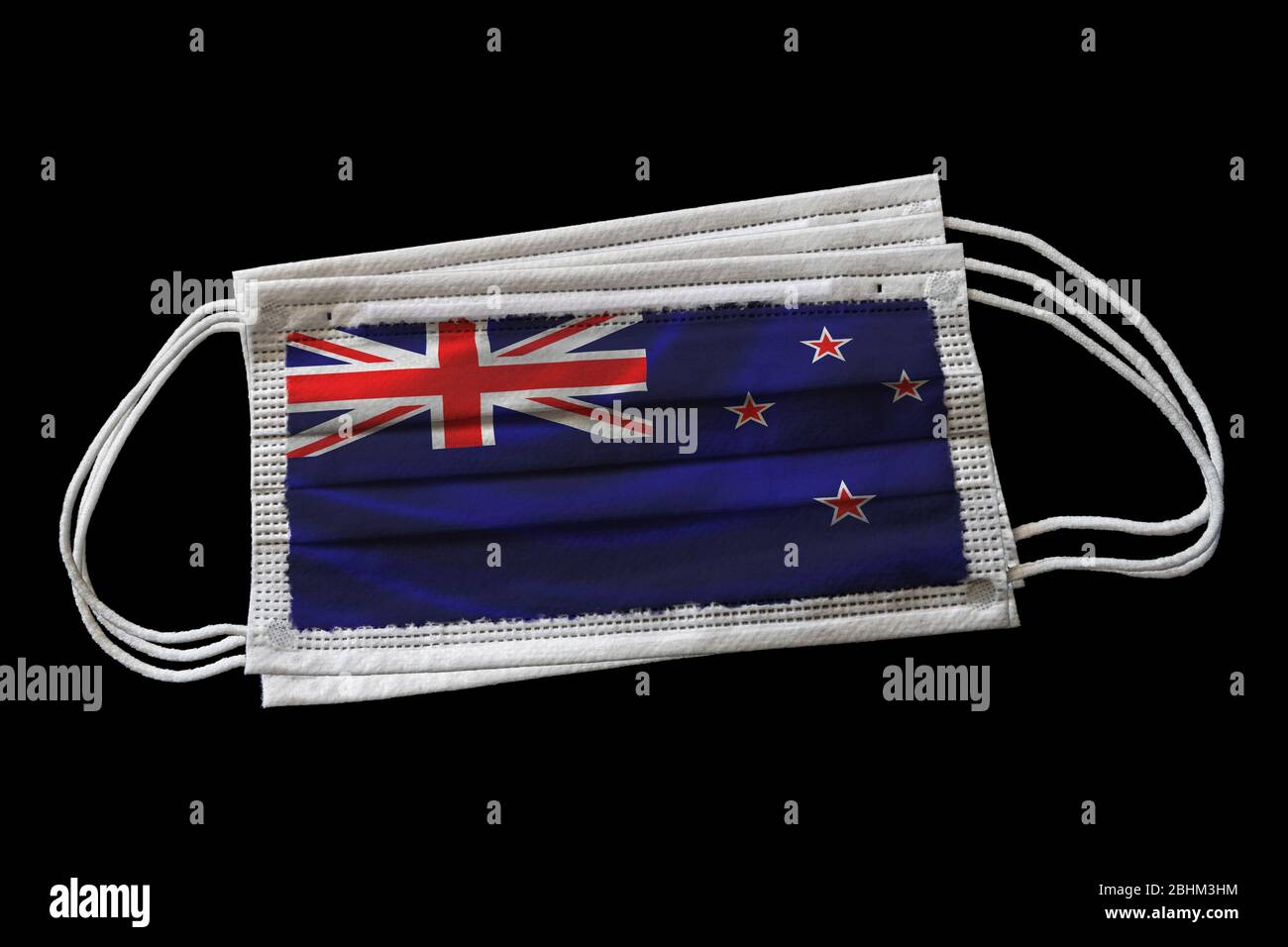 Mehrere chirurgische Gesichtsmasken mit neuseeländischer Flagge bedruckt. Isoliert auf schwarzem Hintergrund. Konzept der Gesichtsmaske Verwendung in der Neuseeländer Bemühungen um CO Stockfoto
