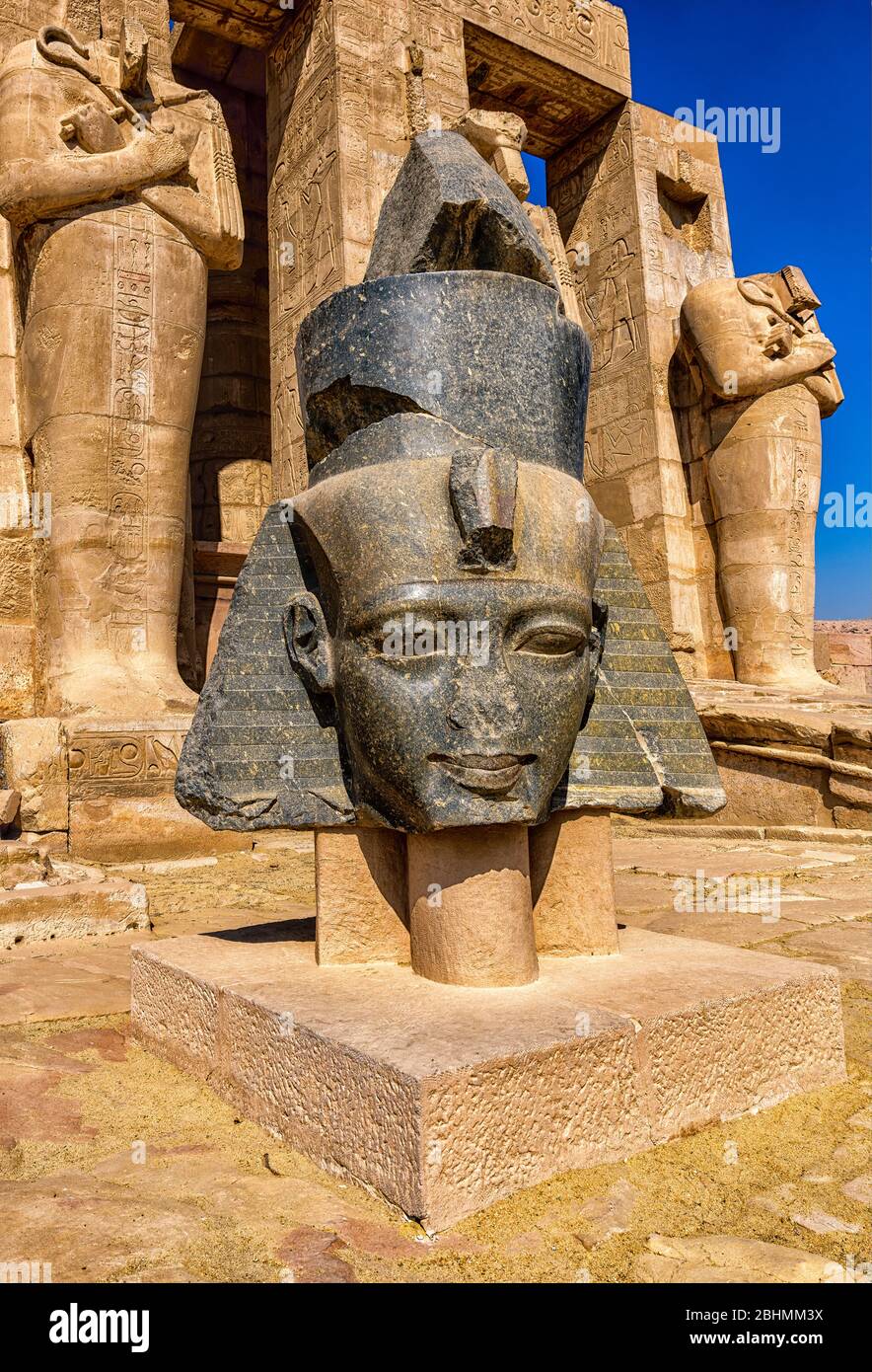 Granitkopf des Pharao Ramesses II vor den Füßen der Osirid-Statuen im Ramesseum Stockfoto