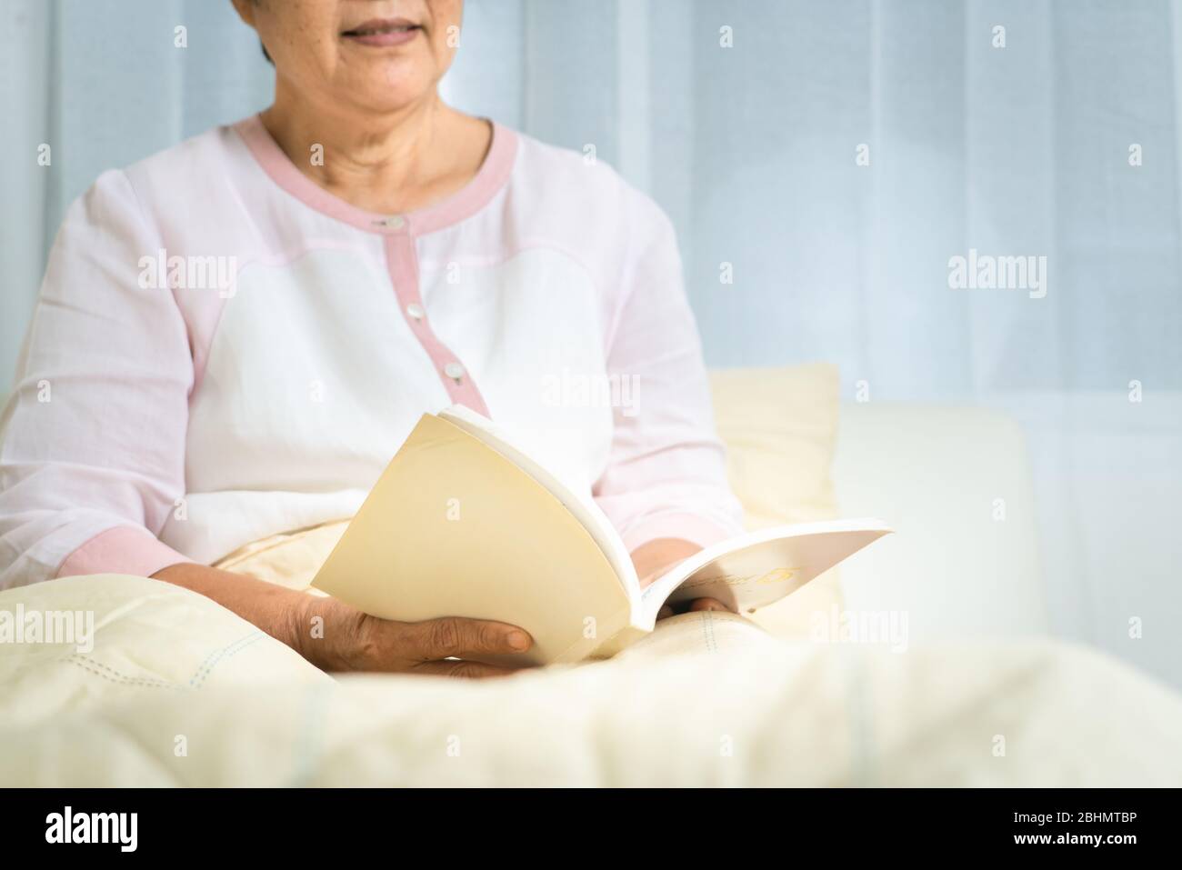 Covid-19 Quarantäneaktivität für ältere Frauen Lesen Sie ein Buch bleiben Sie zu Hause, um Risiken zu vermeiden Stockfoto