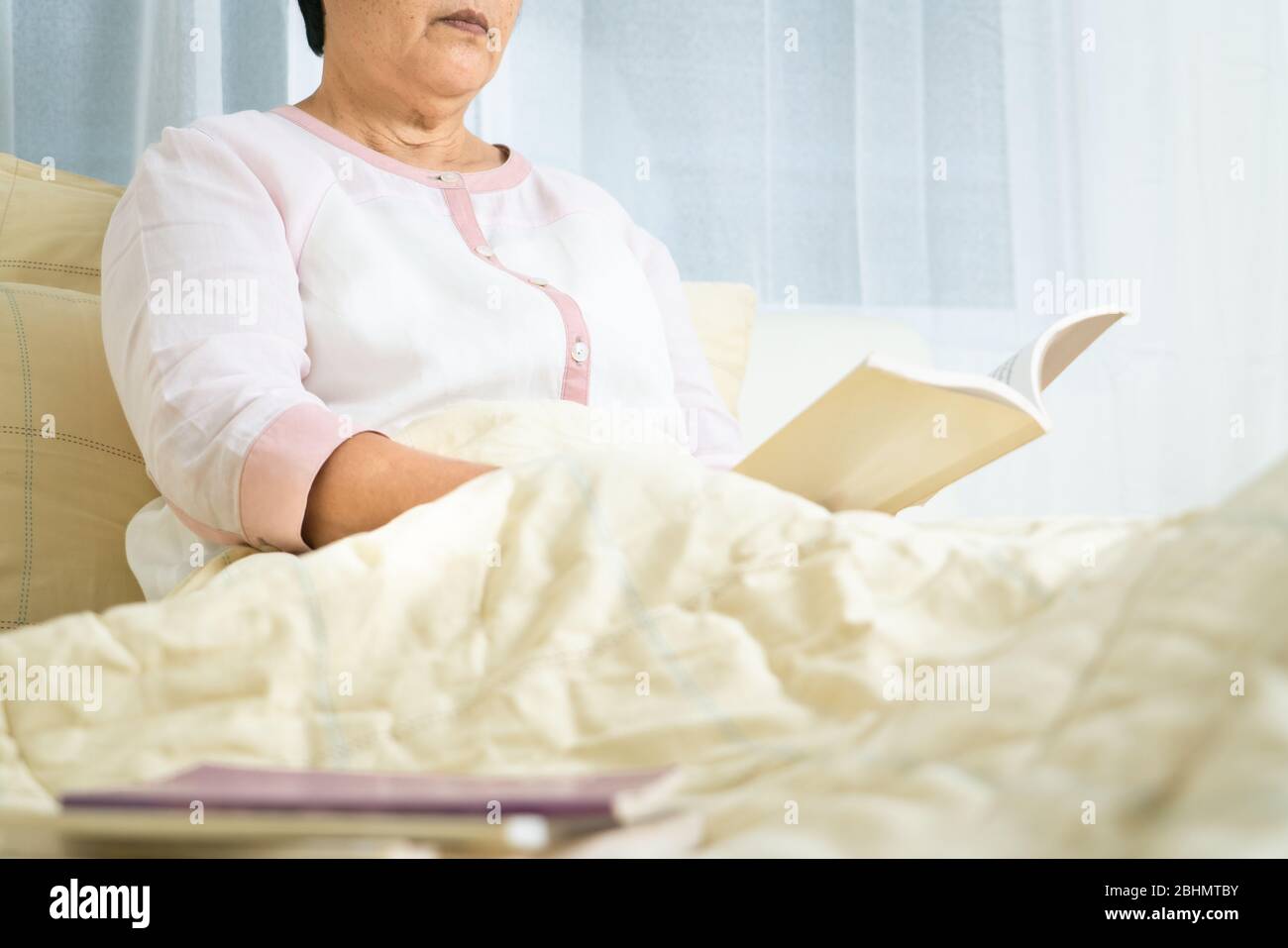 Covid-19 Quarantäneaktivität für ältere Frauen Lesen Sie ein Buch bleiben Sie zu Hause, um Risiken zu vermeiden Stockfoto