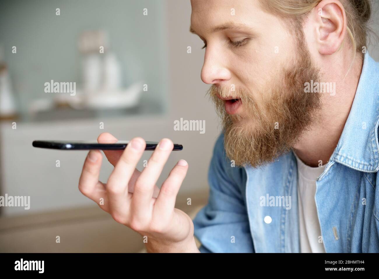 Junger Mann mit virtuellen digitalen Sprachassistenten auf dem Handy, Nahaufnahme. Stockfoto