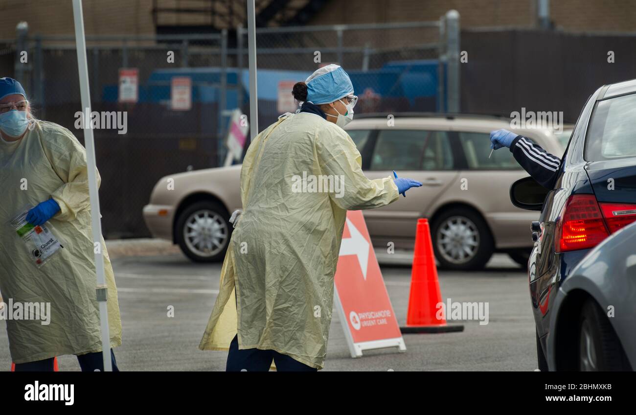 Fahren Sie durch die COVID-19-Tests, Medford, Massachusetts, USA. 25. April 2020. Der Fahrer zeigt dem Techniker am Eingang zum PhysicianOne Urgent Care Drive up COVID-19 Testing eine ID. Stockfoto